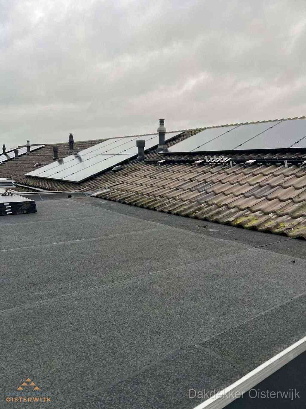 Plat dak inspectie met bitumen bedekking naast schuin pannendak in Oisterwijk